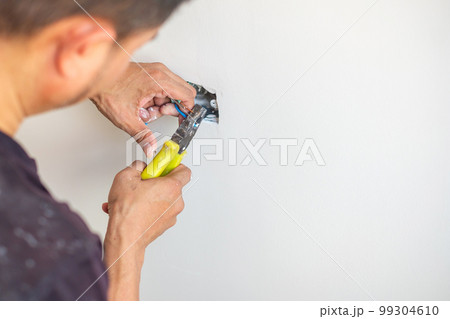 Electrician cuts electrical wires with pliers, Wiring cables installation for socket plug to a concrete. Renovation, Repair, service and development of home and apartment concepts Electrician cuts electrical wires with pliers, Wiring cables installation for socket plug to a concrete. Renovation, Repair, service and development of home and apartment concepts 99304610