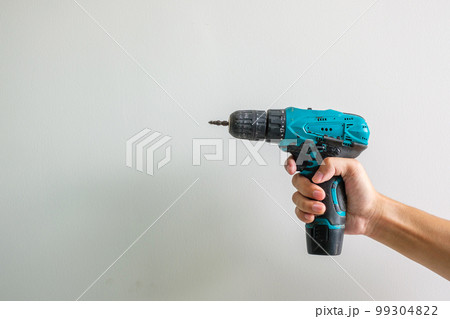 man hand holding cordless screwdriver with wall background, Carpenter working with electric screwdriver on the work 99304822