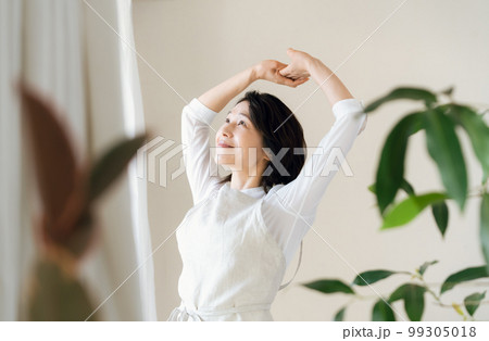窓辺で日光を浴びるミドル女性 99305018