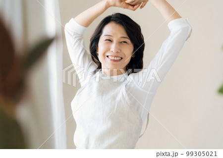 窓辺で日光を浴びるミドル女性 99305021