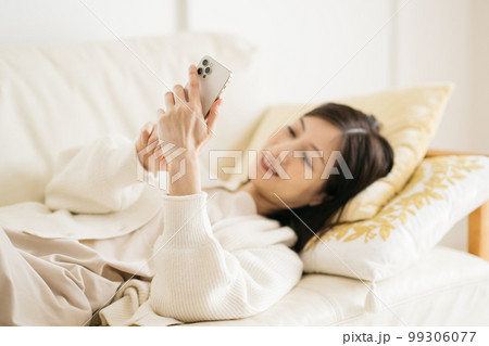 ソファーでスマホを見る女性 99306077