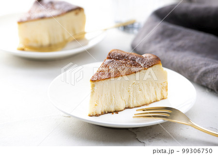 明るいテーブルにバスクチーズケーキと金色のフォーク 99306750