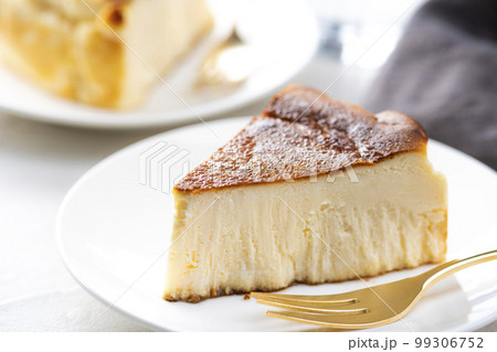 明るいテーブルにバスクチーズケーキと金色のフォーク 99306752