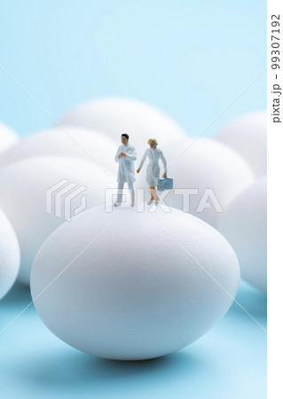水色の背景に生卵とミニチュアの医者 99307192