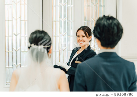 結婚式場のドアを開けるウェディングプランナー・ドアスタッフ・ホテリエの女性と新郎新婦（結婚式） 99309790