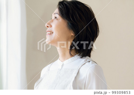 窓辺で日光を浴びるミドル女性 99309853