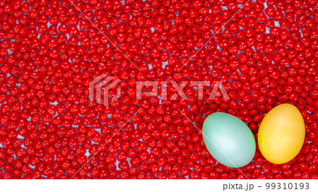 Easter eggs with space for text on red heart candies background. Colorful easter eggs on red background. Top View. Copy Space. Spring dessert. Easter eggs with space for text on red heart candies background. Colorful easter eggs on red background. Top View. Copy Space. Spring dessert. 99310193