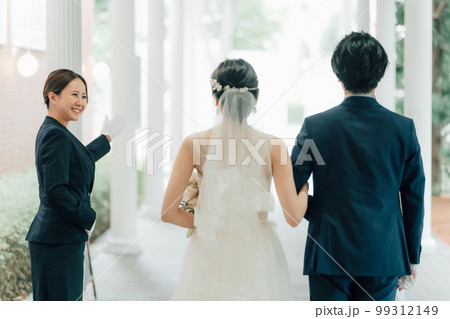 結婚式場を案内するウェディングプランナー・ドアスタッフ・ホテリエの女性と新郎新婦（結婚式） 99312149