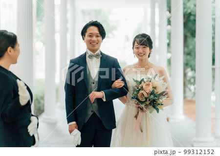 結婚式場を案内するウェディングプランナー・ドアスタッフ・ホテリエの女性と新郎新婦（結婚式） 99312152