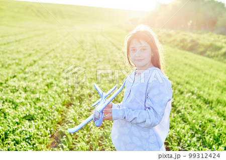 Sincere emotions. Happy little girl running on the field with blue toy plane in their hands. Sincere emotions. Happy little girl running on the field with blue toy plane in their hands. 99312424