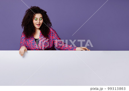 A woman leans her hands on an empty space for text on a purple background. 99313863