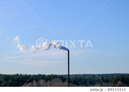 A smoldering factory chimney. Tall metallic smoke stack of incinerator Thick white smoke clouds against blue sky. A smoldering factory chimney. Tall metallic smoke stack of incinerator Thick white smoke clouds against blue sky. 99314314
