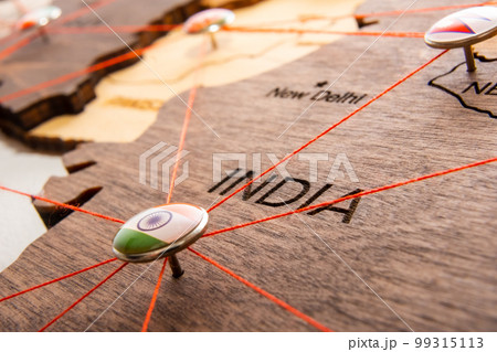 India flag on the pushpin and red threads on the wooden map. Travel or logistic routes. Influence in geopolitics and world economy. India flag on the pushpin and red threads on the wooden map. Travel or logistic routes. Influence in geopolitics and world economy. 99315113