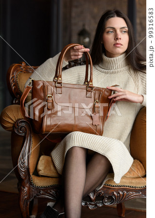 photo of a woman with a brown leather bag with antique and retro look. indoors photo 99316583