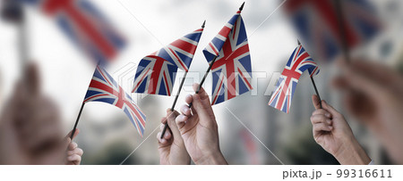 A group of people holding small flags of the United Kingdom in their hands A group of people holding small flags of the United Kingdom in their hands 99316611