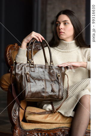 photo of a woman with a brown leather bag with antique and retro look. indoors photo 99316630