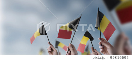 A group of people holding small flags of the Belgium in their hands A group of people holding small flags of the Belgium in their hands 99316692