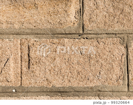 texture of the stone. A yellow stone decorated in the form of a brick in bright sunlight. 99320664