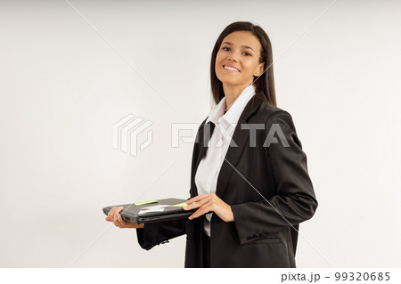 Portrait of happy smiling young woman with laptop in her hands, dressed in white shirt and black jacket on isolated white background. Studio shot of brunette girl with laptop computer. 99320685