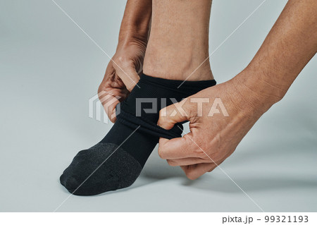 man putting on a compression sock man putting on a compression sock 99321193