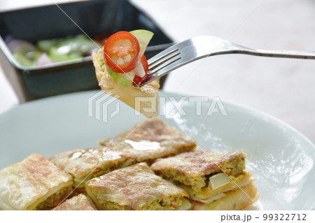 fried Murtabak roti stuffed beef meat stabbing in fork on plate dipping sweet pickled cucumber sauce fried Murtabak roti stuffed beef meat stabbing in fork on plate dipping sweet pickled cucumber sauce 99322712
