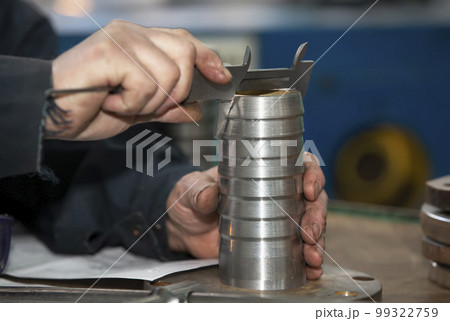 Turning shop or production. Worker's hands hold a metal product coupling. 99322759