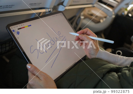 飛行機の機内でタブレットを操作する人　メモアプリに字を書く　 99322875