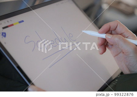 飛行機の機内でタブレットを操作する人　メモアプリに字を書く　 99322876