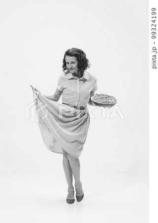 Portrait of beautiful retro woman in vintage fashion style dress holding apple pie. Black and white shot 99324199