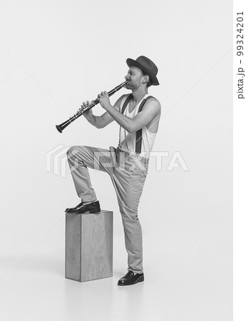 Portrait of young man playing clarinet isolated over white studio background. Expressive performance. Black and white photography Portrait of young man playing clarinet isolated over white studio background. Expressive performance. Black and white photography 99324201