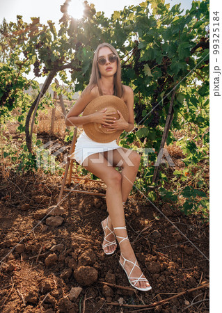 Beautiful young woman with straw hat in vineyard on sunny day 99325184