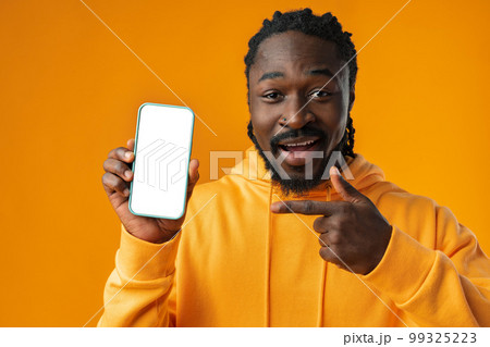 Smiling african man pointing at cellphone with blank screen with copy space Smiling african man pointing at cellphone with blank screen with copy space 99325223