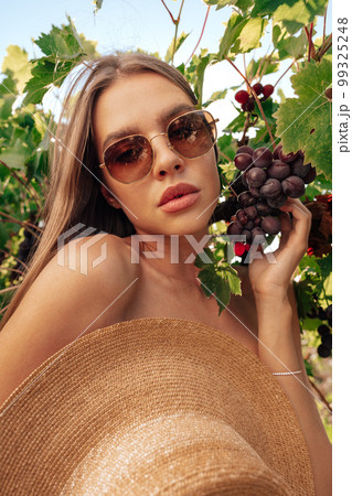 Beautiful young woman with straw hat in vineyard on sunny day Beautiful young woman with straw hat in vineyard on sunny day 99325248