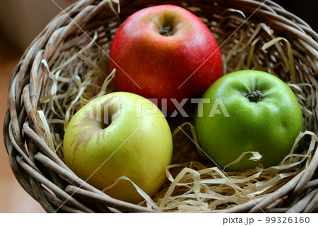 Yellow, Red And Green Apple Fruits In Wood Swarf In A Wicker Pot Closeup Stock Photo Yellow, Red And Green Apple Fruits In Wood Swarf In A Wicker Pot Closeup Stock Photo 99326160