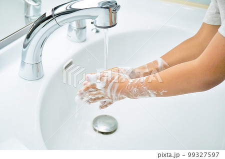 泡立てた石けんで腕まで日常手あらいをした両手を流水で洗い流す幼児 99327597