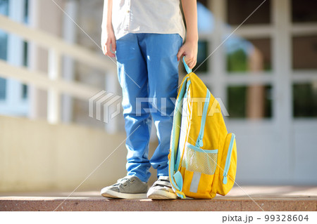 Little student with a backpack on the steps of the stairs of school building. Close-up of child legs, hands and schoolbag of boy standing on staircase of schoolhouse. Kids back to school Little student with a backpack on the steps of the stairs of school building. Close-up of child legs, hands and schoolbag of boy standing on staircase of schoolhouse. Kids back to school 99328604