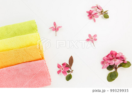 New folded microfiber cloth for cleaning on white with spring flowers background. Cleaning micro fabric towels for dusting and polishing. Domestic household cleaning service concept. Top view New folded microfiber cloth for cleaning on white with spring flowers background. Cleaning micro fabric towels for dusting and polishing. Domestic household cleaning service concept. Top view 99329935
