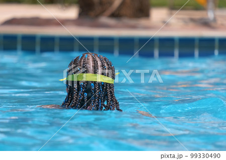 Young child girl in goggles exercises swimming in blue pool water. Summer recreation activity concept Young child girl in goggles exercises swimming in blue pool water. Summer recreation activity concept 99330490