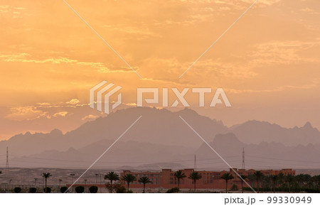 Sunset landscape with remote hotel complex against dark mountain peaks in egyptian desert Sunset landscape with remote hotel complex against dark mountain peaks in egyptian desert 99330949
