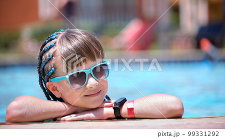Portrait of happy child girl relaxing on swimming pool side on sunny summer day during tropical holidays 99331292