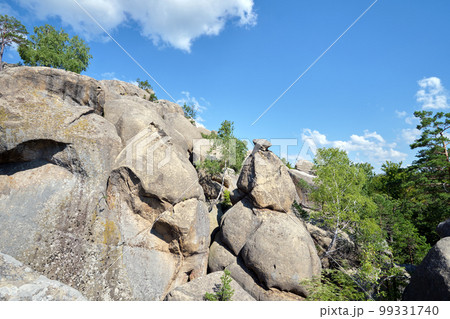 Huge rocky boulder formations high in mountains with growing trees on summer sunny day Huge rocky boulder formations high in mountains with growing trees on summer sunny day 99331740