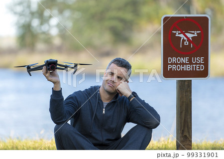 Drone operator is disappointed because he isn't allowed to fly his quadcopter in national park no drone area. Man is unable to use his UAV near restriction notice sign. Airspace use regulations 99331901