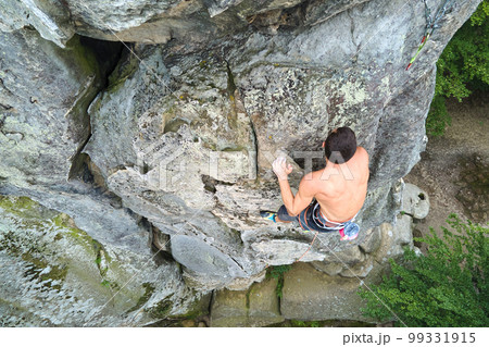 Determined climber clambering up steep wall of rocky mountain. Sportsman overcoming difficult route. Engaging in extreme sports and rock climbing hobby concept. Determined climber clambering up steep wall of rocky mountain. Sportsman overcoming difficult route. Engaging in extreme sports and rock climbing hobby concept. 99331915
