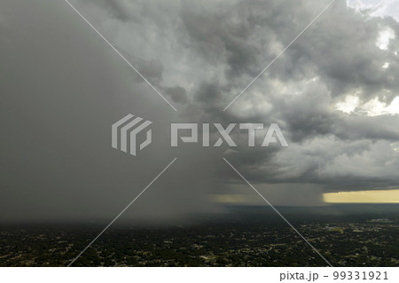 Dark stormy clouds forming on gloomy sky during heavy rainfall season over suburban town area 99331921