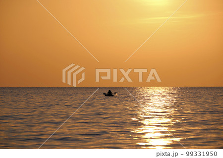 Dark figure of sportsman rowing alone on his kayak boat on sea water at sunset. Active extreme sports concept 99331950