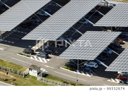 Aerial view of solar panels installed over parking lot with parked cars for effective generation of clean energy Aerial view of solar panels installed over parking lot with parked cars for effective generation of clean energy 99332674