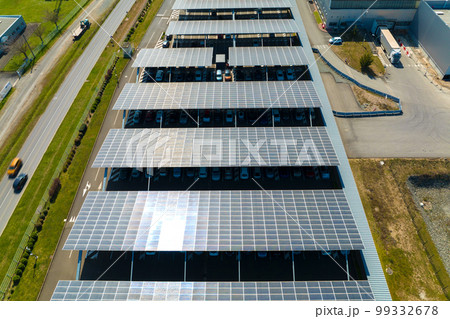Aerial view of solar panels installed as shade roof over parking lot with parked cars for effective generation of clean electricity. Photovoltaic technology integrated in urban infrastructure Aerial view of solar panels installed as shade roof over parking lot with parked cars for effective generation of clean electricity. Photovoltaic technology integrated in urban infrastructure 99332678