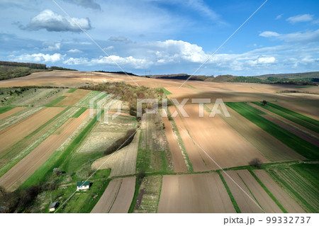 Aerial view of plowed agricultural fields with cultivated fertile soil prepared for planting crops between green woods in spring 99332737