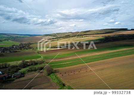 Aerial view of plowed agricultural fields with cultivated fertile soil prepared for planting crops between green woods in spring 99332738