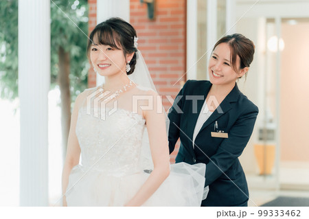 結婚式場を案内するウェディングプランナー・ブライダルアテンダー・介添人の女性と花嫁・新婦（結婚式） 99333462